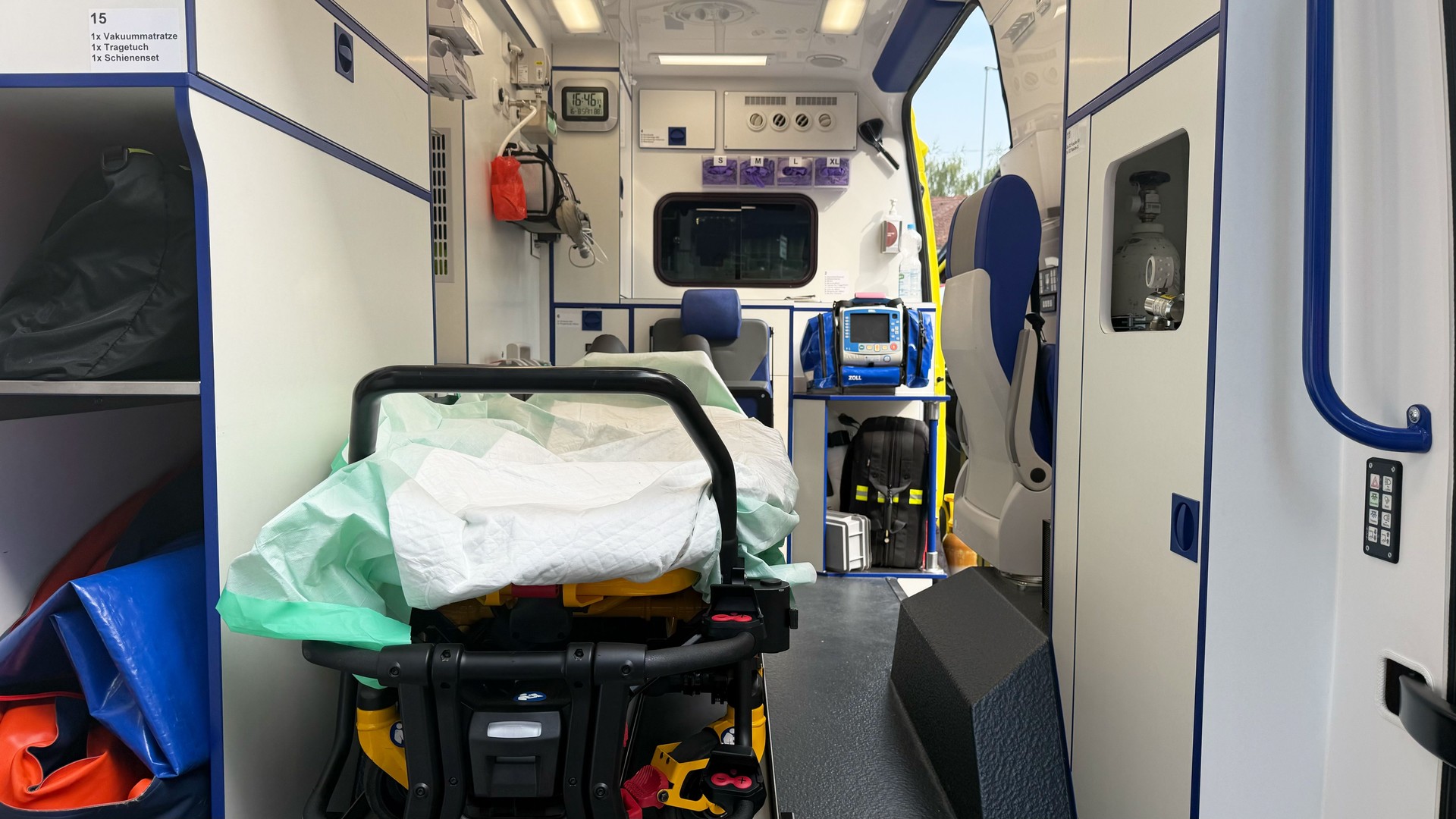 Ambulance emergency vehicle on white background with open rear doors, fully equipped interior showing stretcher, patient bed and medical equipment, modern paramedic transport and healthcare service concept